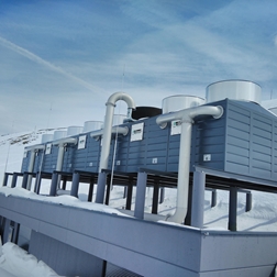 Impianto tecnico su un tetto piano in un paesaggio montano innevato.