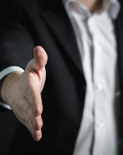 Person in a suit extending their hand for a handshake.