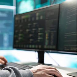 Person arbeitet an Computermonitoren.